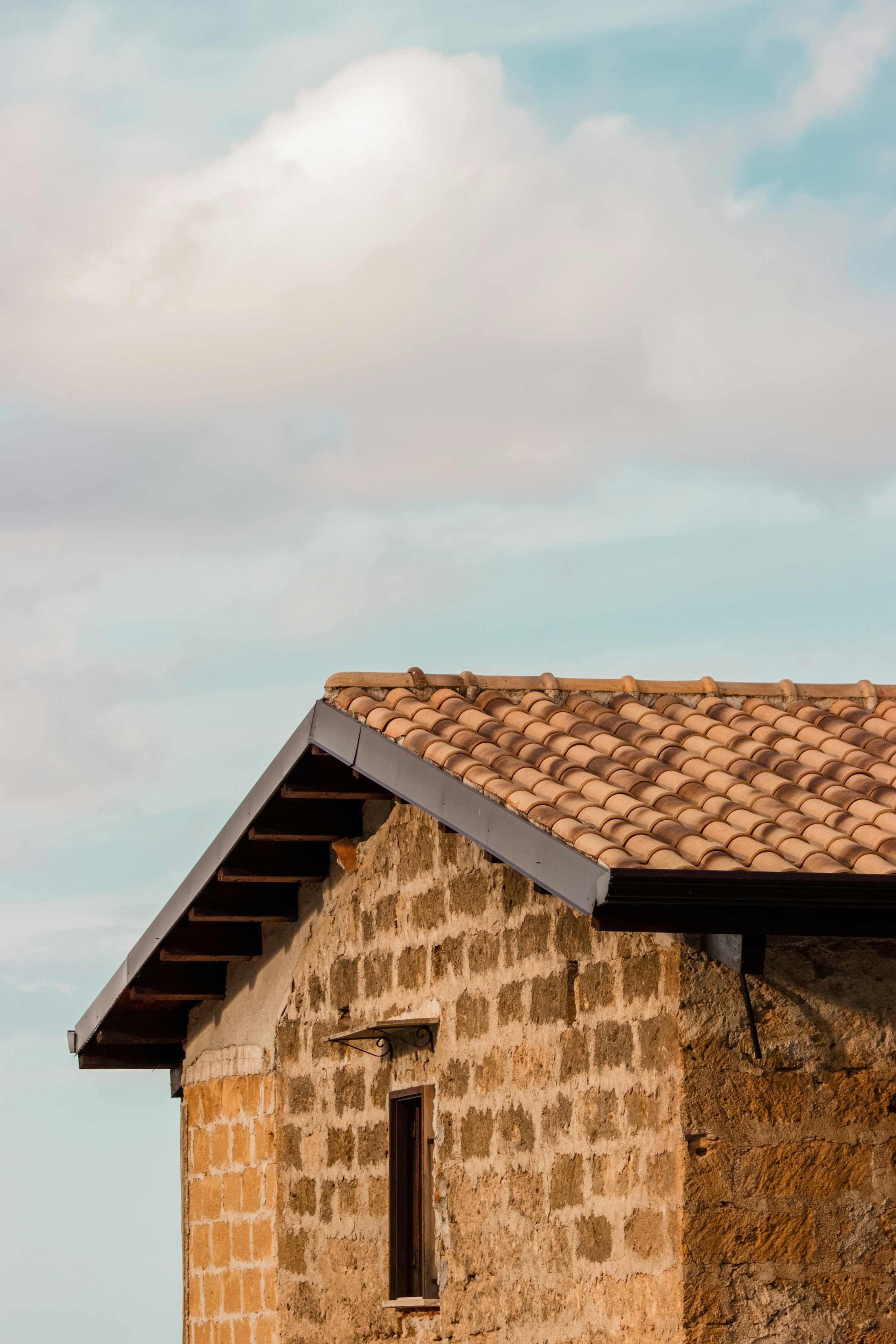 Casa rústica con techo de teja de barro y muro de piedra